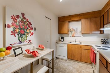 A kitchen with wooden cabinets and a table with a bowl of fruit on it